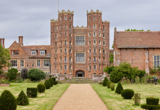 Foto af Layer Marney Tower i det østlige England, en historisk bygning og feriepark omgivet af haver.