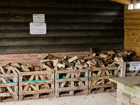 Leña apilada en un cobertizo del parque vacacional BoerenBed Layer Marney Tower, Este de Inglaterra, Reino Unido.
