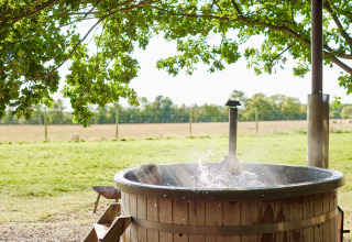 Bain chaud extérieur en bois sous les arbres à BoerenBed Layer Marney Tower, parc de vacances dans l'est anglais.