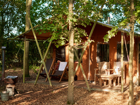 Cozy wooden cabin porch at BoerenBed Layer Marney Tower, with deck chairs and rustic seating in forest setting.