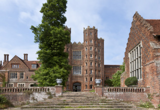 View of the historic Layer Marney Tower holiday park in England, featuring red brickwork and grand steps.