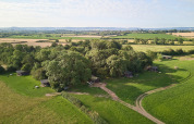 Vue aérienne du parc de vacances BoerenBed Moor Farm dans le sud-ouest de l'Angleterre avec cabanes et champs verts.