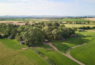 Luftfoto af BoerenBed Moor Farm feriested i det sydvestlige England med grønne marker og træhytter.
