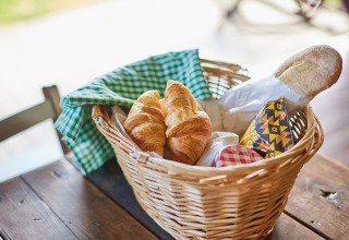 Fletkurv med croissanter, baguette og syltetøj på træbord ved BoerenBed Moor Farm, Sydvest England.