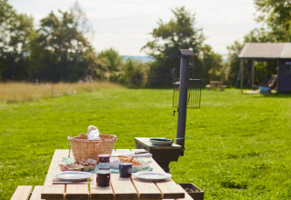 Mesa de picnic al aire libre con desayuno y cesta en un campo verde en BoerenBed Moor Farm, Inglaterra.