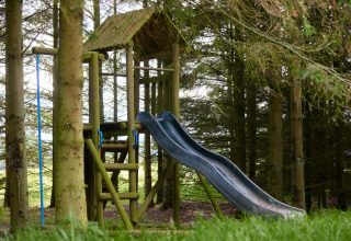 Houten speeltuin met glijbaan en klimrek tussen bomen bij BoerenBed Hidcote Manor Farm, West Midlands.