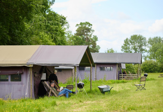 Personas relajándose fuera de tiendas glamping en BoerenBed Hidcote Manor Farm, West Midlands, Reino Unido.