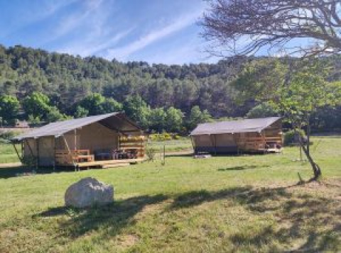 Zwei Safarizelte auf dem Agricampeggio Tasteria in Italien, umgeben von Wiese und Bäumen bei sonnigem Wetter.