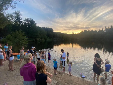 Famiglie e bambini si ritrovano al lago del campeggio Le Paradou, Francia, al tramonto.