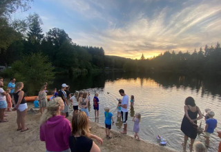 Famiglie e bambini si ritrovano al lago del campeggio Le Paradou, Francia, al tramonto.