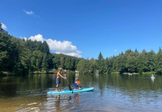 Two people paddleboarding on a calm lake at Campsite Le Paradou in Auvergne-Rhône-Alpes, France.