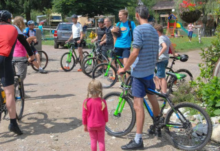 Ciclisti e bambini si ritrovano al campeggio Le Paradou, parco vacanze in Auvergne-Rhône-Alpes, Francia.