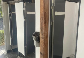 Bagni con divisori grigi e bianchi e cestino su palo in legno presso il campeggio Le Paradou.