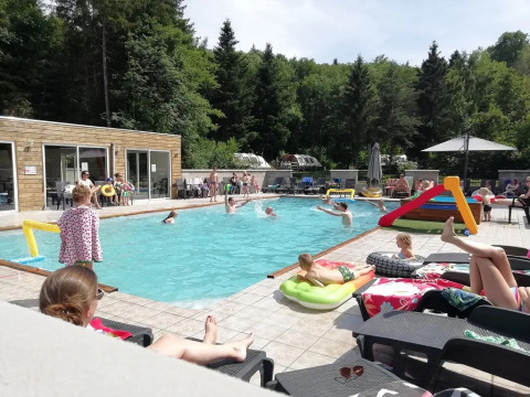 Famiglie si rilassano e giocano a bordo piscina al campeggio Le Paradou in Auvergne-Rhône-Alpes, Francia.