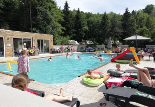 Famiglie si rilassano e giocano a bordo piscina al campeggio Le Paradou in Auvergne-Rhône-Alpes, Francia.