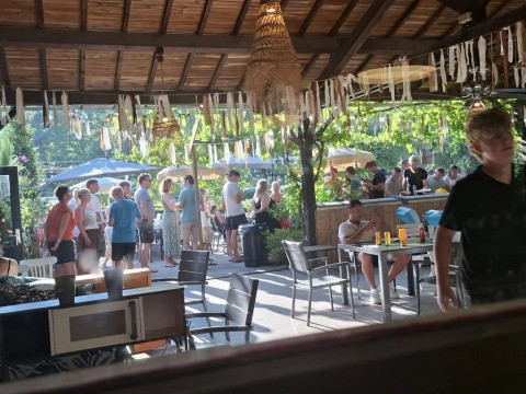 Zona pranzo all'aperto presso il campeggio Le Paradou in Auvergne-Rhône-Alpes, Francia, piena di ospiti.