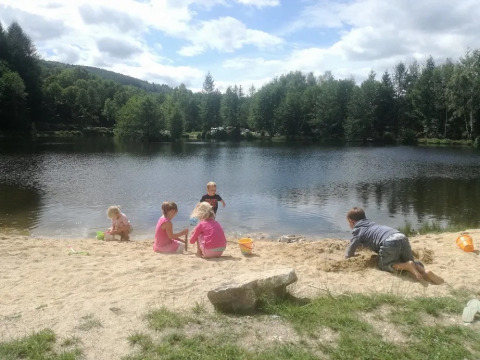 Bambini che giocano sulla spiaggia sabbiosa accanto a un lago al campeggio Le Paradou in Francia.