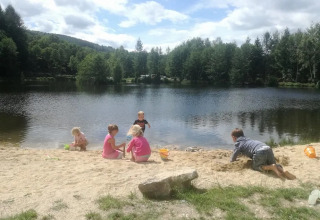 Bambini che giocano sulla spiaggia sabbiosa accanto a un lago al campeggio Le Paradou in Francia.