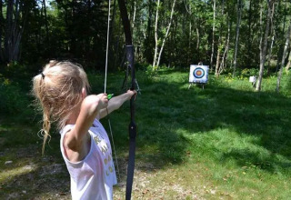 Una bambina mira con arco e freccia a un bersaglio al campeggio Le Paradou, Auvergne-Rhône-Alpes, Francia.
