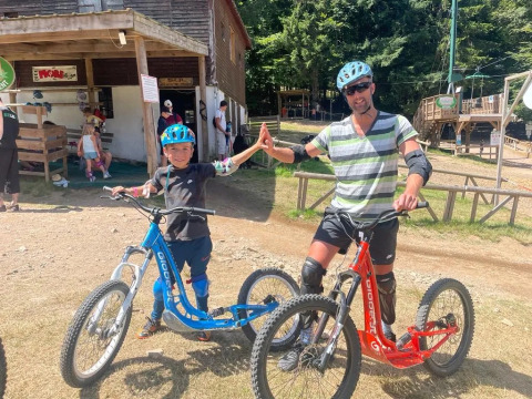 Due persone con casco e protezioni fanno un high five vicino a monopattini in un villaggio vacanze in Francia.