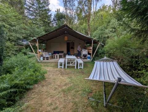 Campeggio Le Paradou in Alvernia-Rodano-Alpi, Francia, con tenda, tavoli da picnic e amaca nella natura.