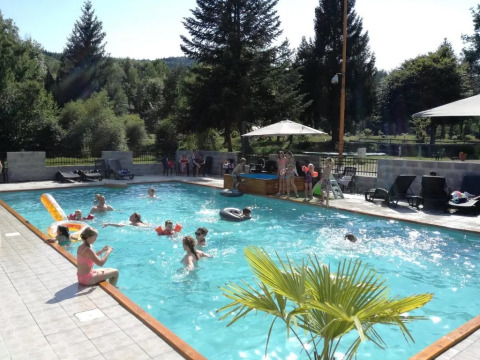 Bambini e adulti si godono una giornata di sole in piscina al campeggio Le Paradou in Alvernia-Rodano-Alpi, Francia.