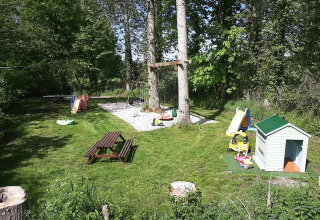 Area giochi al campeggio Le Bois Coudrais in Bretagna, Francia, con altalene, scivolo e casetta per bambini.