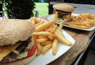 Succulenti hamburger e patatine fritte serviti all'aperto al campeggio Le Bois Coudrais in Bretagna, Francia.