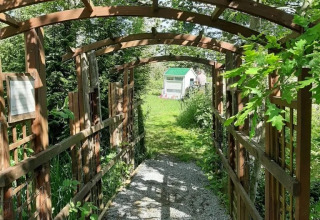 Ingresso al parco giochi nel campeggio Le Bois Coudrais in Bretagna, Francia, circondato dal verde.