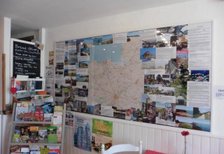 Angolo informativo con mappa, opuscoli e bacheca presso il campeggio Le Bois Coudrais in Bretagna, Francia.