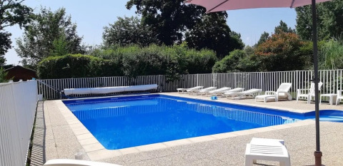 Piscina all'aperto con lettini e recinzione bianca a Le Bois Coudrais, campeggio in Bretagna, Francia.