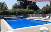 Outdoor swimming pool with loungers and white fence at Campsite Le Bois Coudrais in Brittany, France.