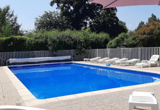 Piscine extérieure avec transats et clôture blanche au camping Le Bois Coudrais en Bretagne, France.