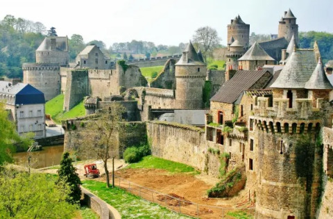Un imponente castello medievale circondato dal verde vicino a Cuguen, in Bretagna, Francia, sotto un cielo limpido.