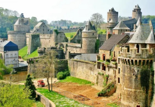 Un imponente castello medievale circondato dal verde vicino a Cuguen, in Bretagna, Francia, sotto un cielo limpido.