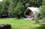 Tente safari du camping Le Bois Coudrais en France, entourée de pelouse verte et d’arbres feuillus.