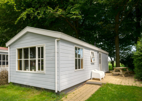 Outdoor view of the Chalet lodge with light blue wooden siding, white windows, and patio seating area.