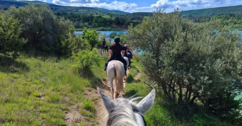 Grupo montando a caballo junto a un lago entre vegetación en el parque de vacaciones de Provence-Alpes-Côte d’Azur.