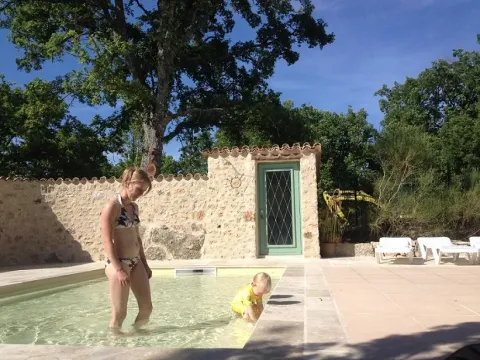A woman and small child play in a shallow pool by a stone wall at Campsite Avelanède, Provence, France.