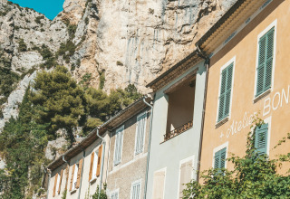 Gezellig terras met parasols naast kleurrijke huizen en een rotswand in de Provence-Alpes-Côte d’Azur, Frankrijk.
