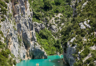 Personas en kayak en aguas turquesas rodeadas de acantilados en el camping Avelanède, Provenza, Francia.