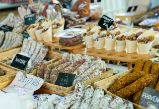 Varietà di salumi e salsicce francesi tradizionali su una bancarella di mercato con cartelli dei gusti.