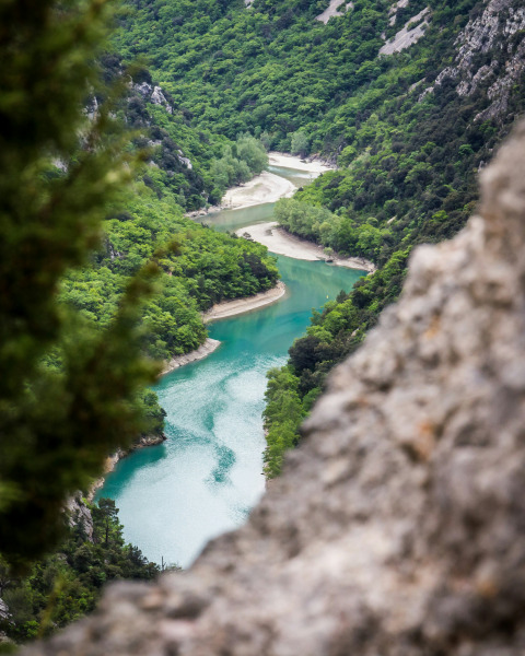 View of a winding turquoise river through green hills seen from Campsite Avelanède, Provence-Alpes-Côte d’Azur, France.