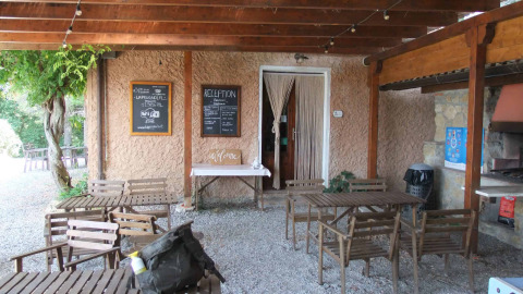 Buitenreceptie en zitruimte bij Agricampeggio La Prugnola in Toscane, Italië, met houten stoelen en bordjes.