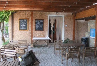 Buitenreceptie en zitruimte bij Agricampeggio La Prugnola in Toscane, Italië, met houten stoelen en bordjes.