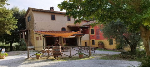 Boerderijwoning met buitenzitje en bomen bij Agricampeggio La Prugnola, een vakantiepark in Toscane, Italië.