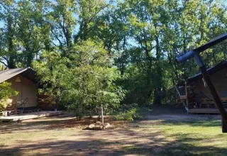 Due tende safari presso il campeggio Avelanède in Francia immerse tra alberi verdi.