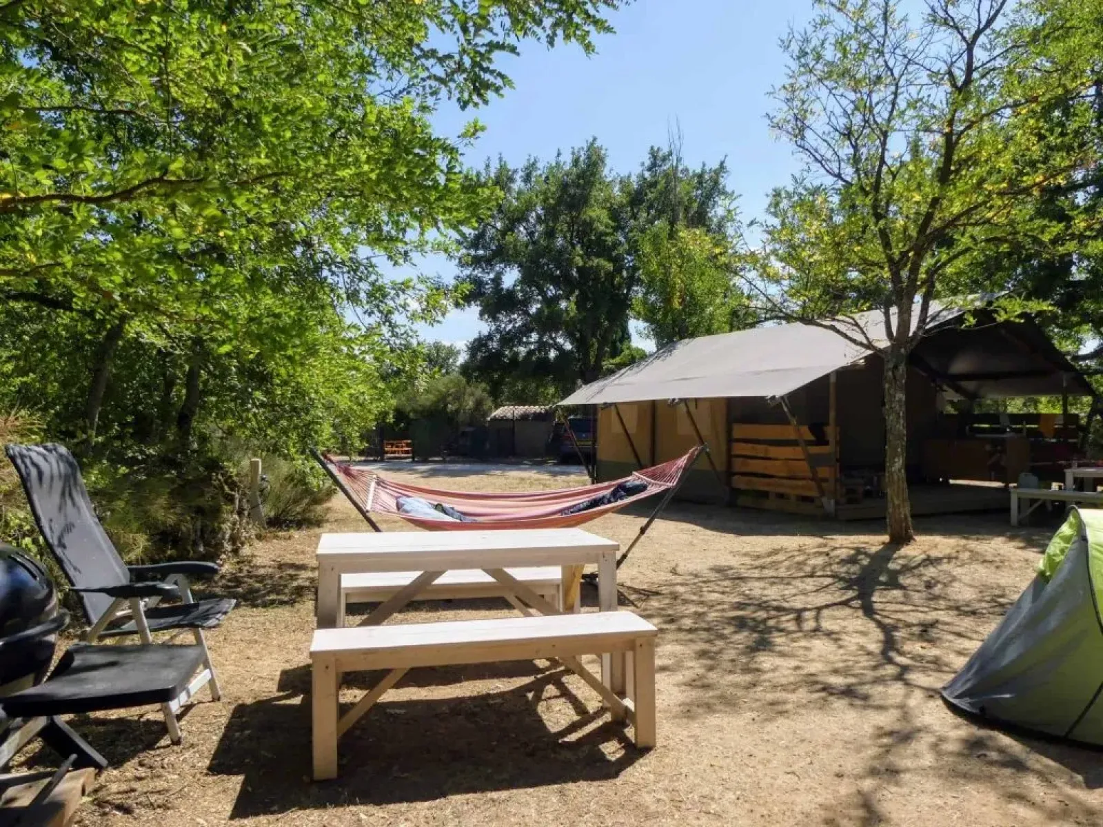 Buitencamping met safaritent, hangmat, picknicktafel en stoelen op Camping Avelanède in Frankrijk.