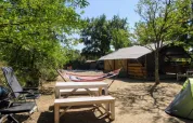 Udendørs campingplads med safaritelte, hængekøje, picnicbord og stole på Campsite Avelanède i Frankrig.