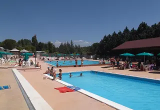 Piscina all'aperto con persone, ombrelloni e aree relax al Camping Pian di Boccio in Umbria, Italia.